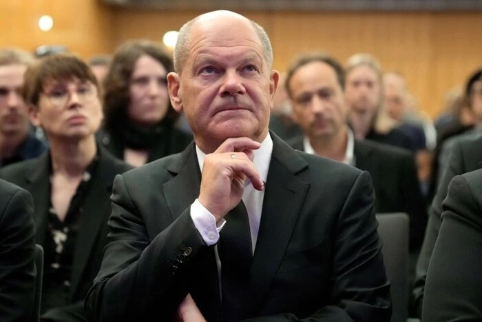 A man hugs Scholz with money scattered in the background